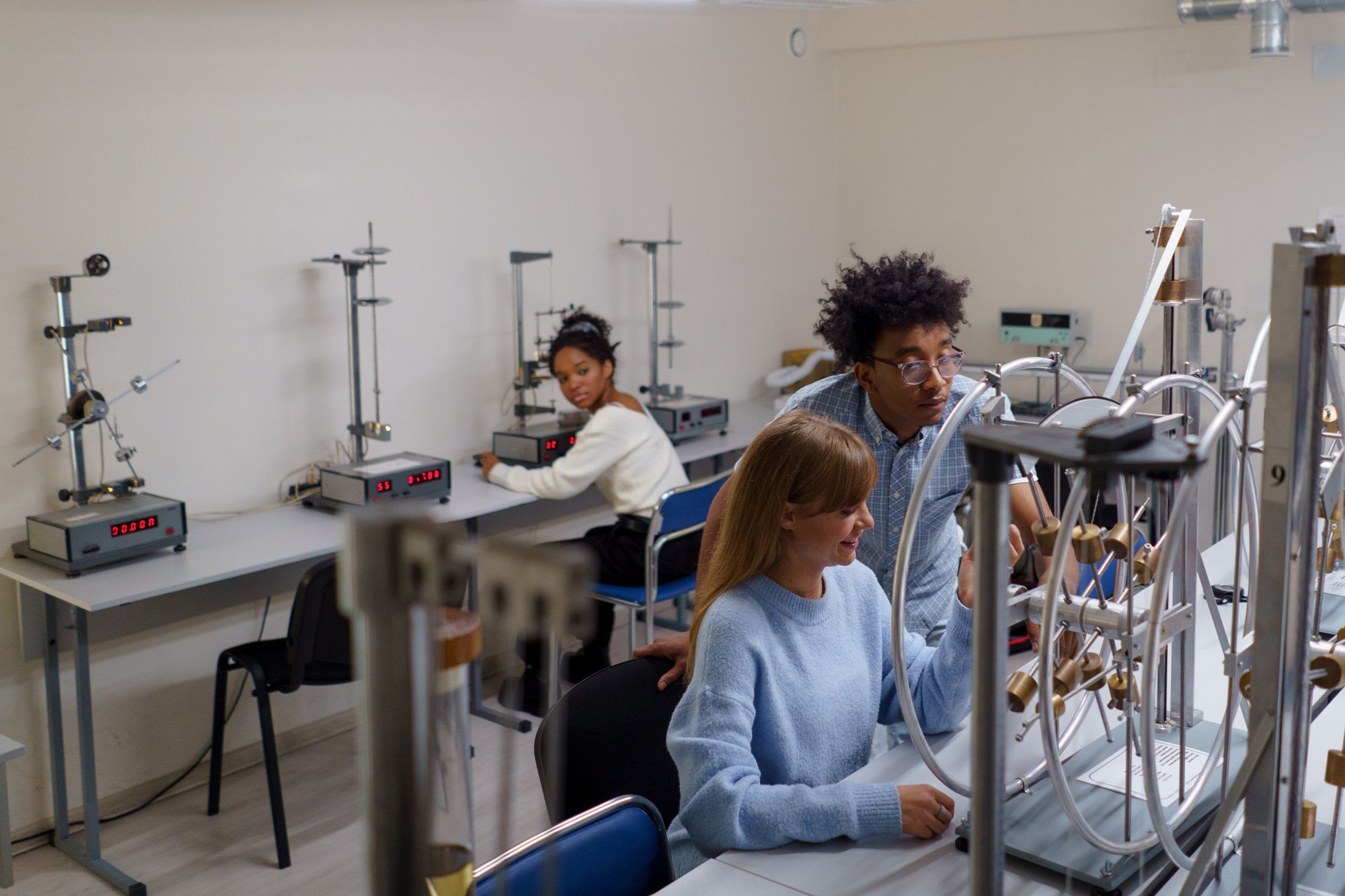 University students collaborating around mechanical test equipment in an engineering laboratory.