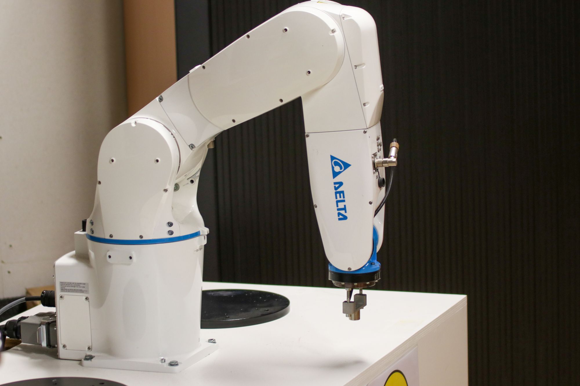 White industrial robotic arm positioned over a precision work surface.